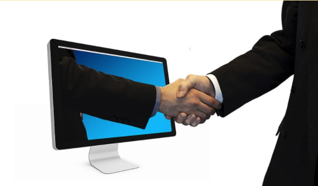 Two people shaking hands through computer screen - symbolizing the b2b sales through social media channels