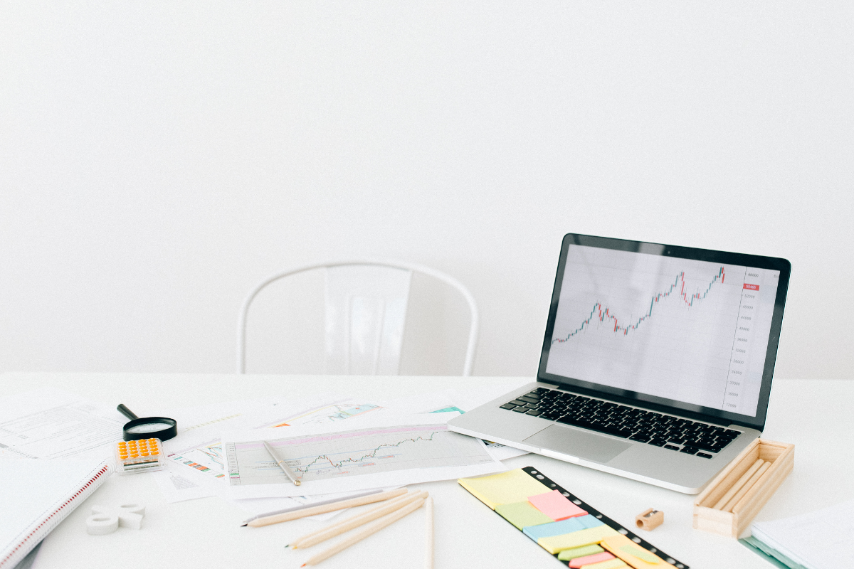 A workspace with a laptop displaying a rising stock market graph, financial documents, and office supplies, symbolizing data-driven strategies in B2B account-based marketing.